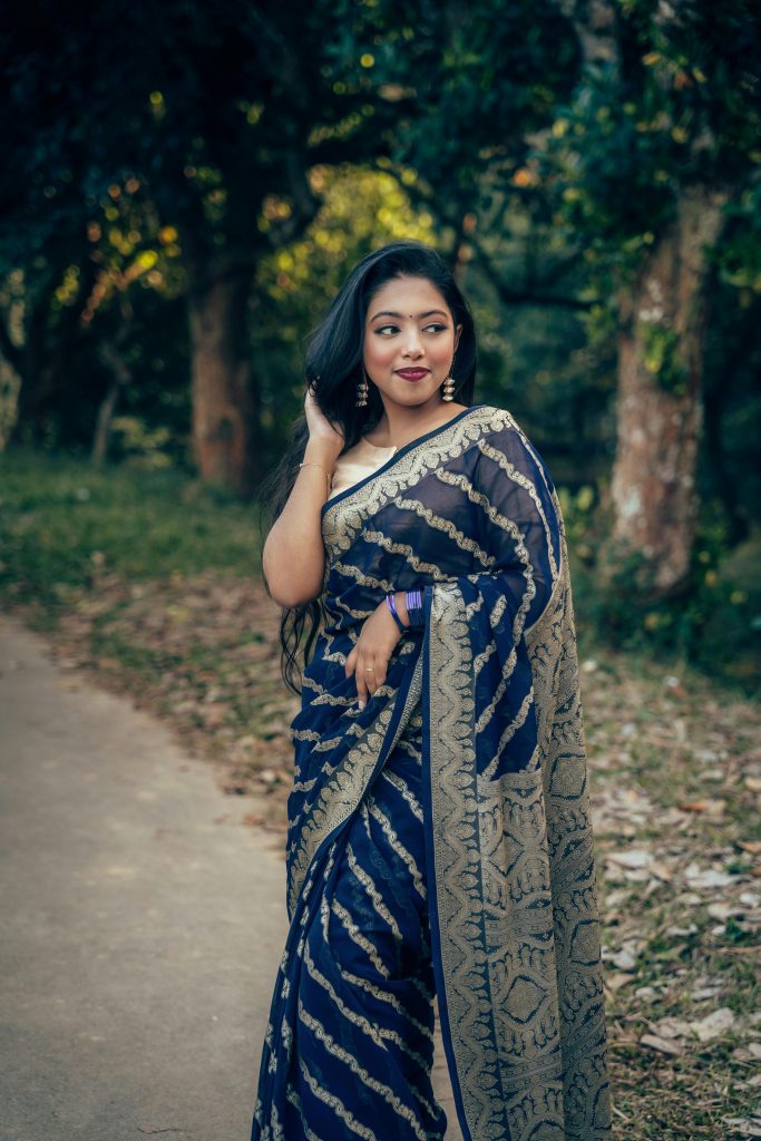 Graceful woman in a traditional saree poses in a natural setting in Comilla, Bangladesh.