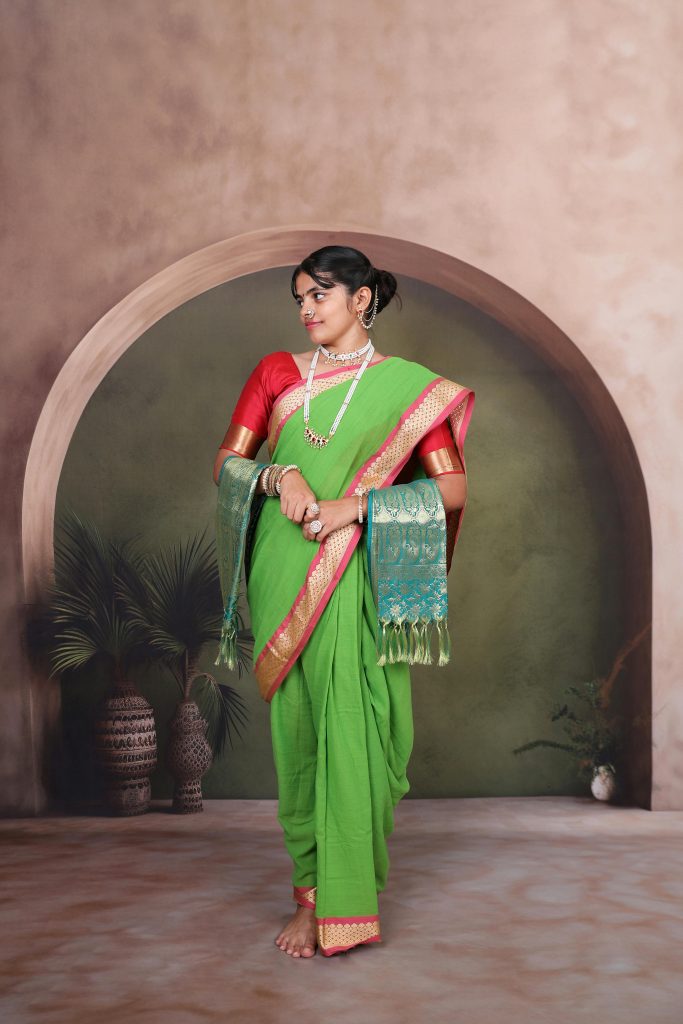 A beautiful Indian woman in a vibrant green saree posing elegantly in a studio setting.